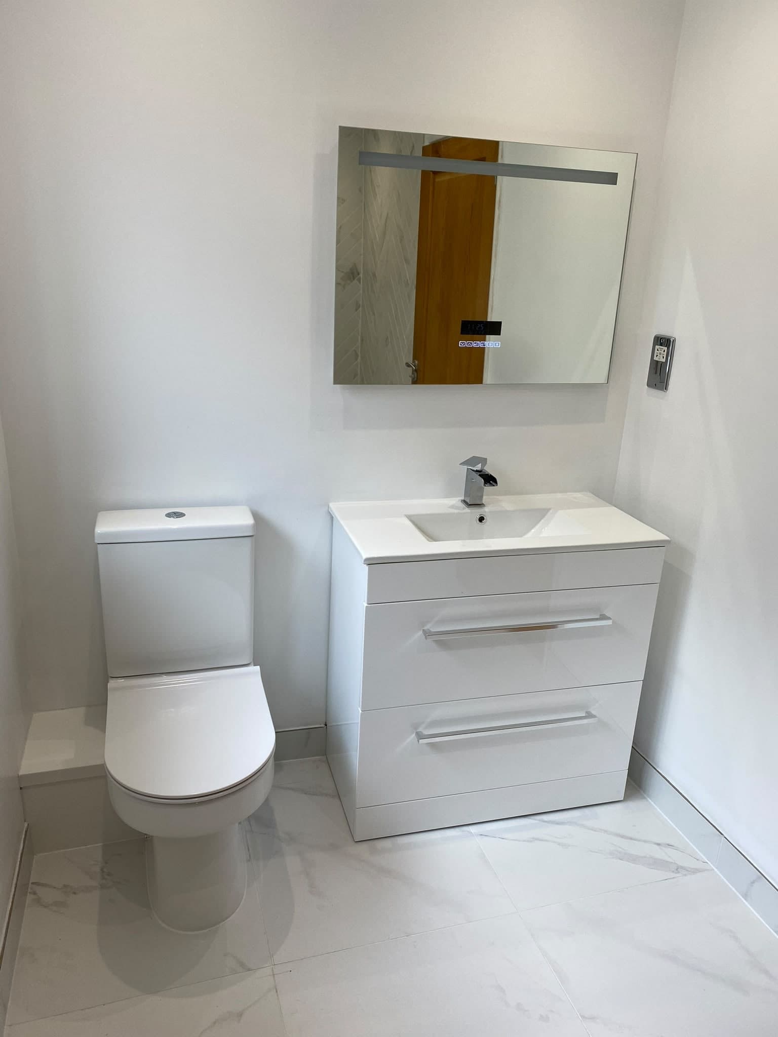 New bathroom with white vanity unit, mirror cabinet and marble-effect tiles