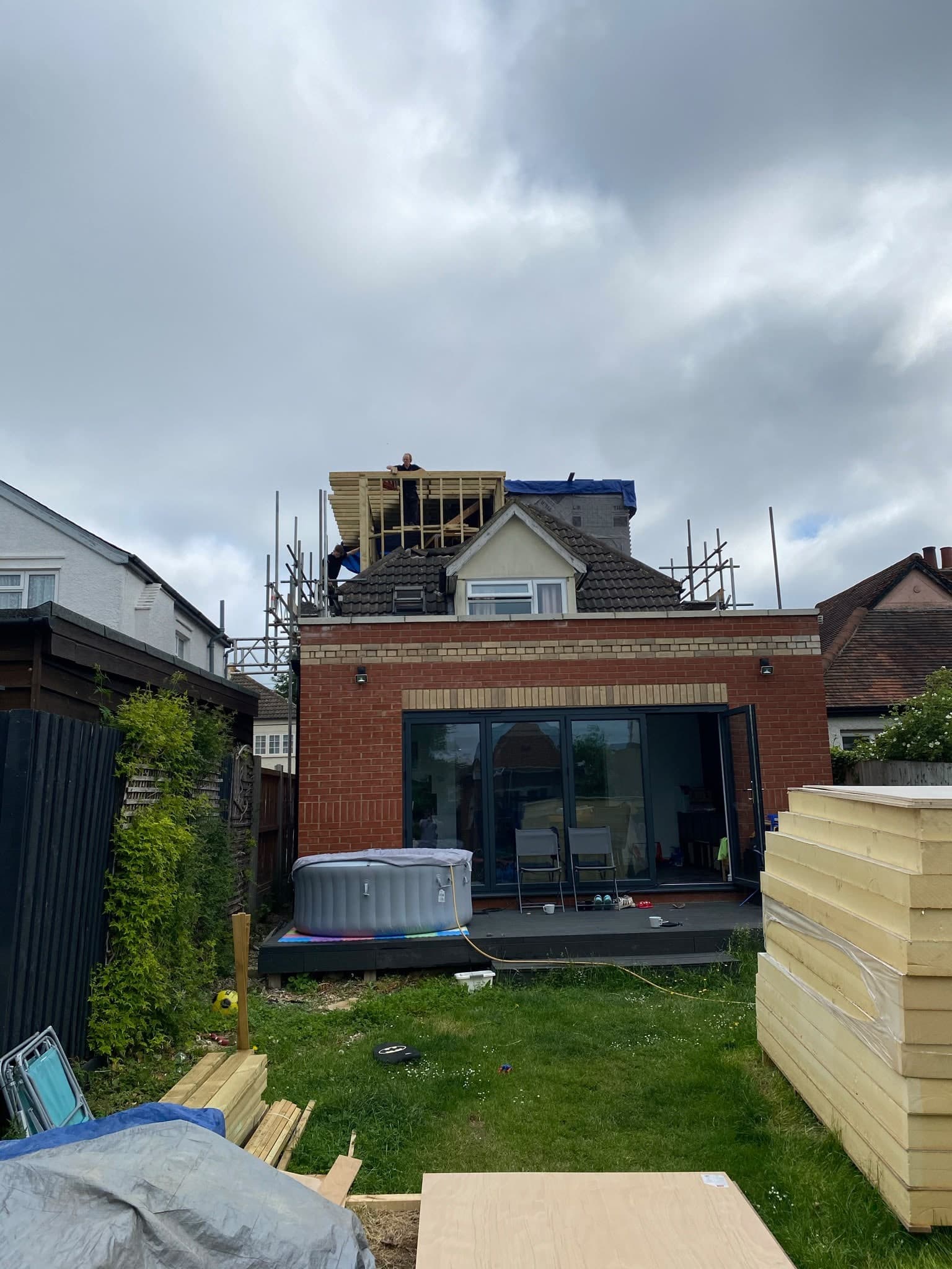 Brick rear extension with bi-fold doors finished and in use, the loft dormer above still under scaffold