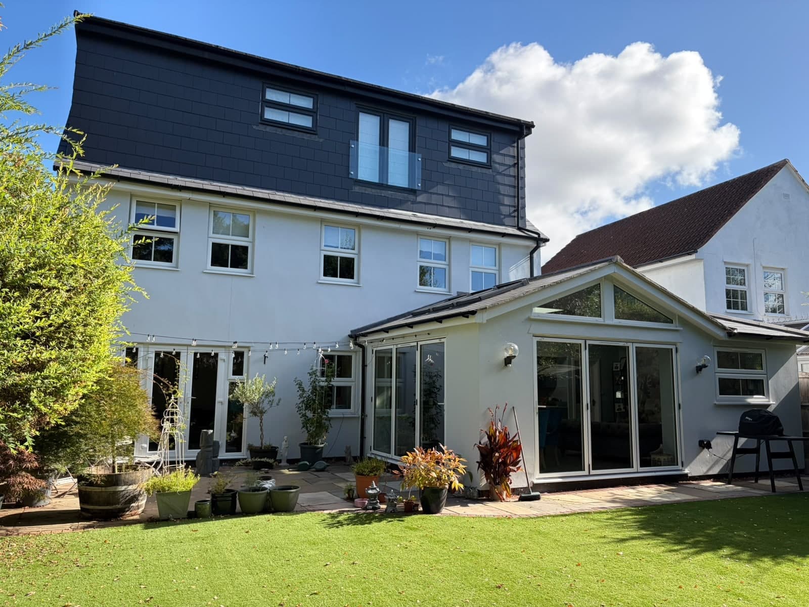 Finished gable-ended rear extension with bi-fold doors on a white rendered detached house, loft dormer above
