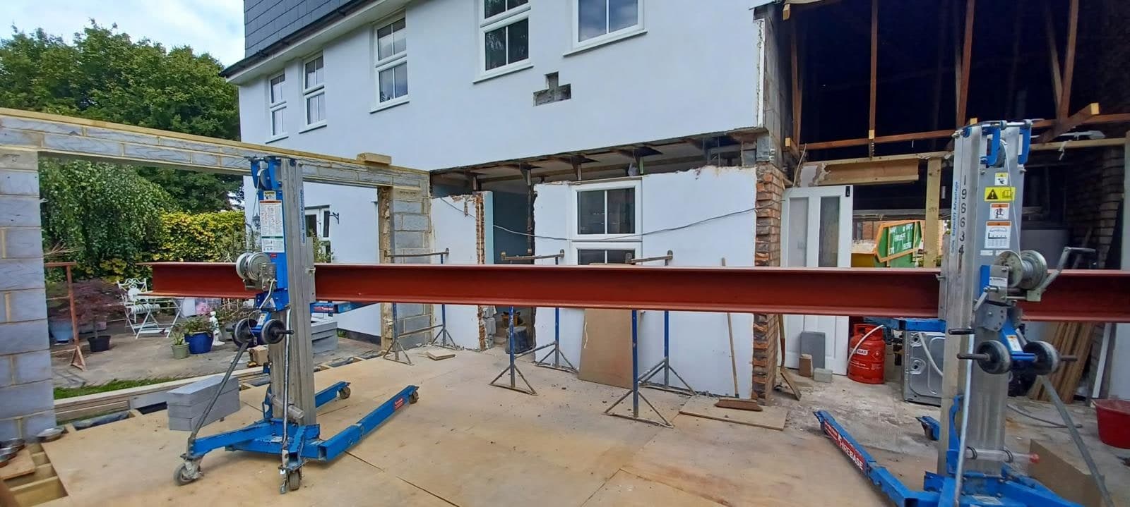 Long steel beam supported on props across the rear of the house