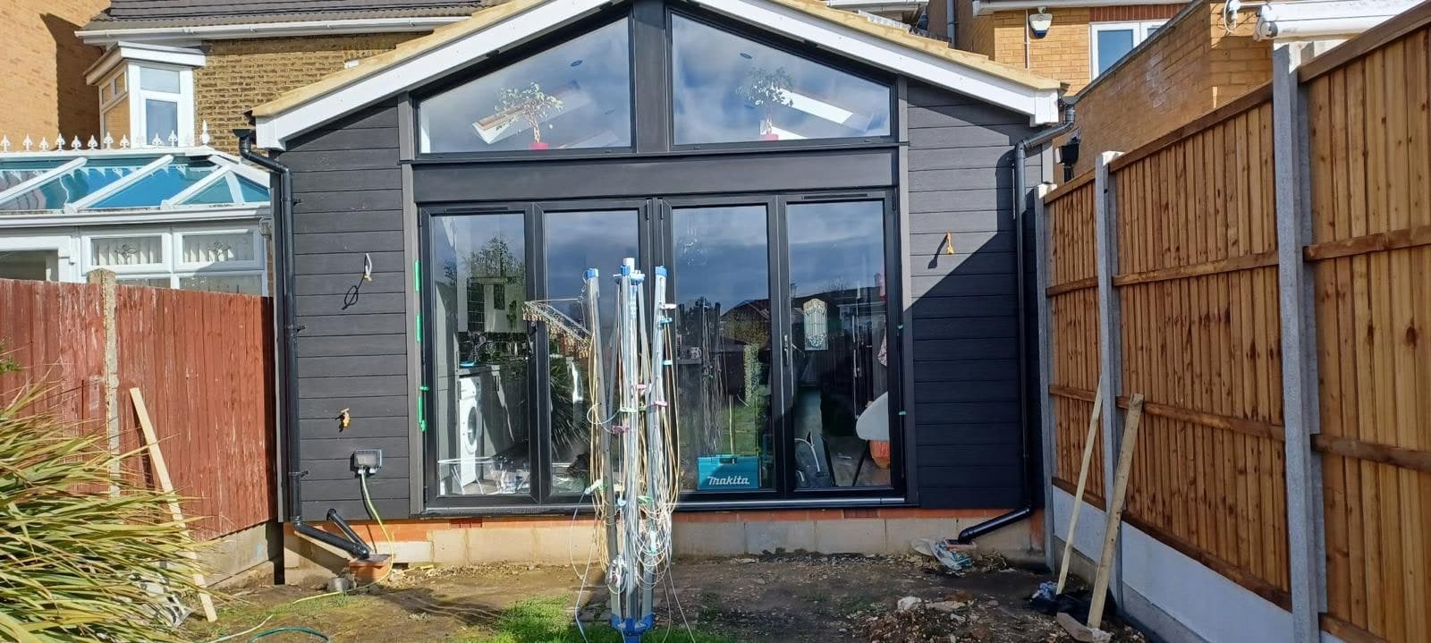 Grey-clad gable extension with glazed apex and bi-fold doors, patio still to lay