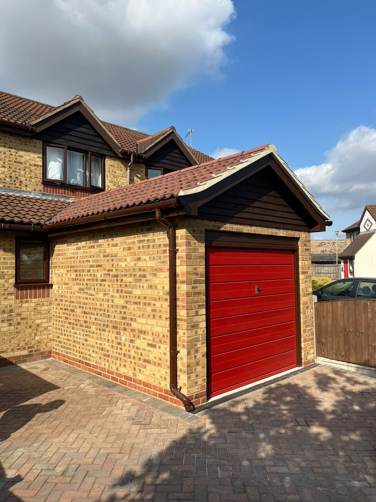 Garage extended forward in matching brick with a new red door