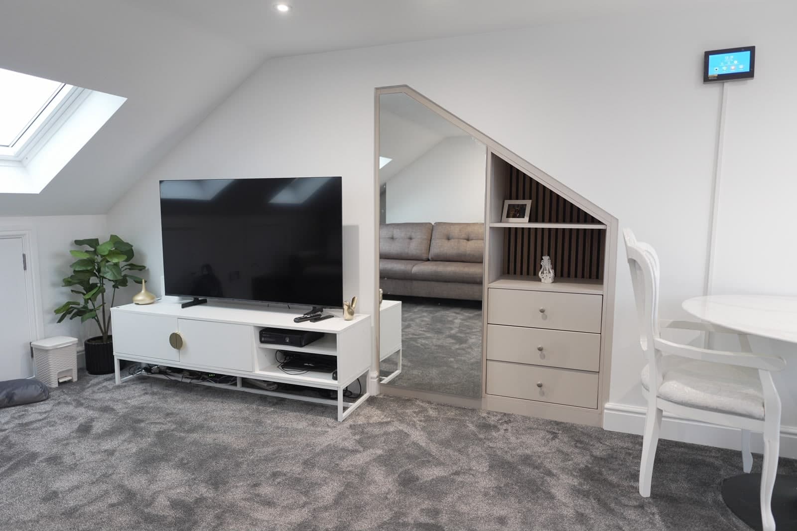 Loft room with television and eaves shelving