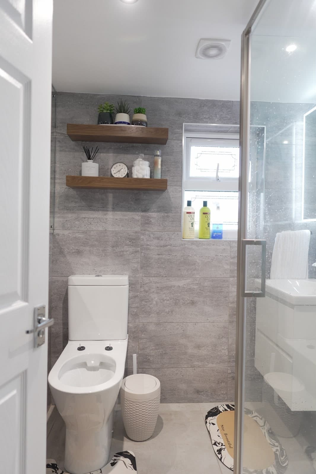 Loft en-suite with floating shelves and grey wall tiles