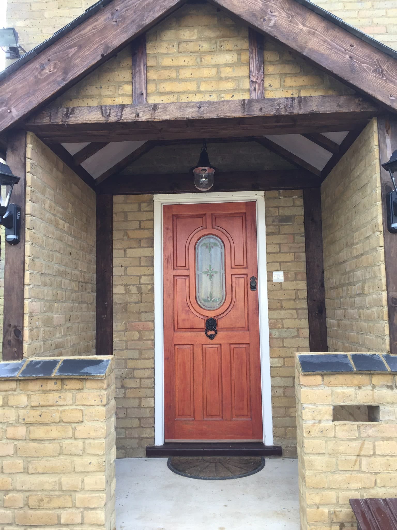 Oak-framed porch canopy over a red front door