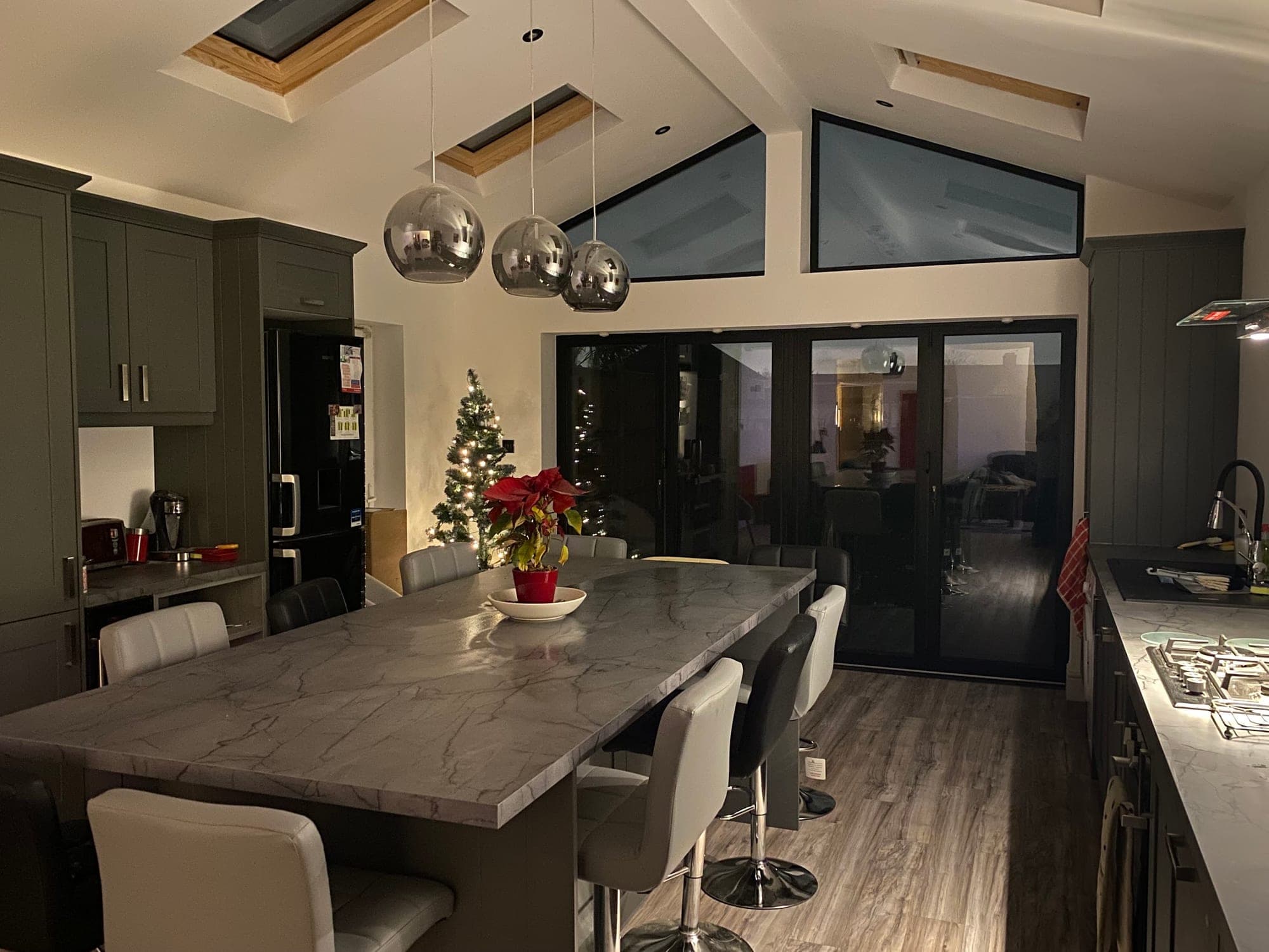 Kitchen extension built by F.W.S Builders: marble-effect island under pendant lights, glazed gable and bi-fold doors